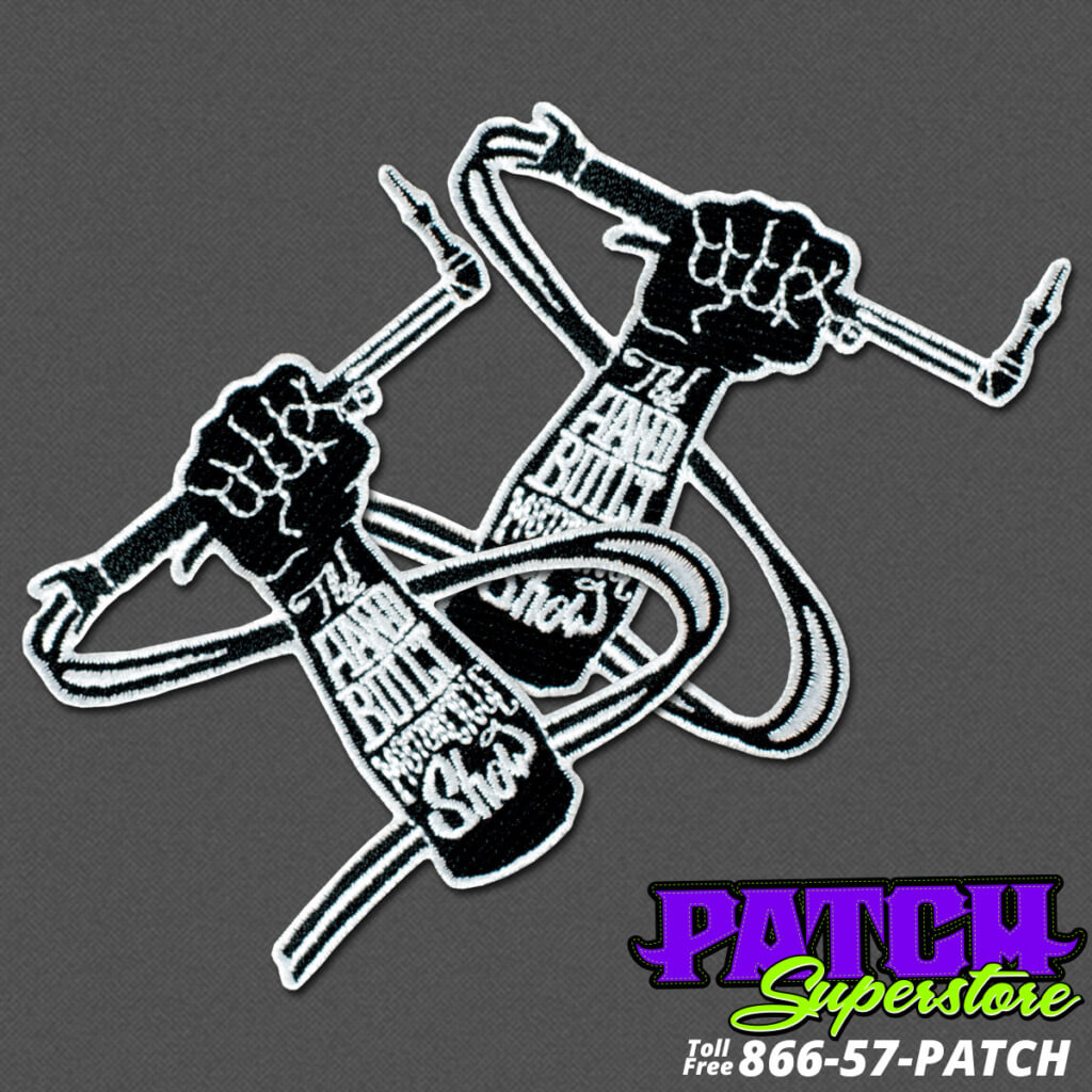 arm with fist holding a soldering gun with "the hand that built motorcycle shop" black and white biker patch