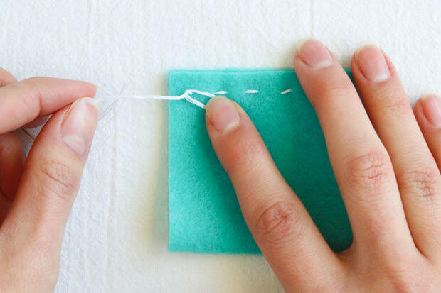 example of a tie off stitch. hands holding a piece of fabric, tieing the knot